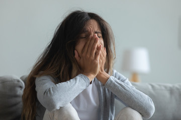 Depressed young woman crying, covering face with hands close up, suffering from break up with...