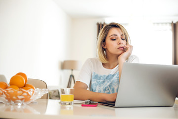 Young woman working from home at kitchen table.