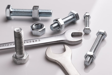 Set of bolts and nuts close up. Bolts and nuts on a white mirror surface of the table. Fixing tool.
