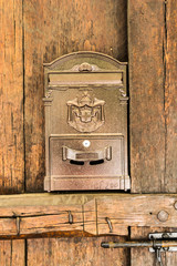 Postal mailbox in a golden color on an old door from massive wood.