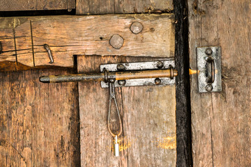 Old latch with padlock on an old door from massive wood.