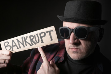 Adult man shows inscription bankrupt. Financial ruin. Man points his finger at the bankrupt slogan....
