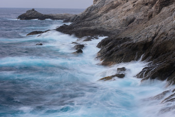 waves crashing on rocks at the blue hour in Ikaria