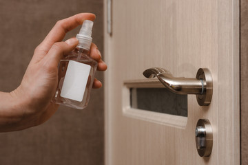 Cleaning door handles with an antiseptic during a viral epidemic. Close up view of a man hand using...