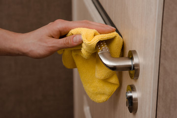 Cleaning door handles with an antiseptic during a viral epidemic. Close up view of a man hand using...