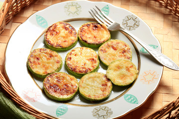 Homemade Fried sliced courgette. Zucchini cut into pieces served on plate or bowl on wicker wooden table. Vegetable vegetarian food dish close-up