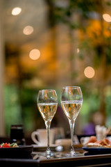 Two glasses of white wine with meal on summer terrace bokeh sunlight leaf cafe