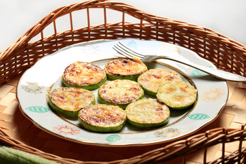Homemade Fried sliced courgette. Zucchini cut into pieces served on plate or bowl on wicker wooden table. Vegetable vegetarian food dish