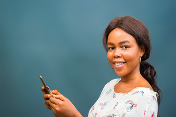 young beautiful african lady feeling excited about the transaction she carried out her cellphone, mobile phone, phone and holding her credit card