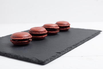 Obraz na płótnie Canvas delicious chocolate macarons on Slate plate on white wooden background