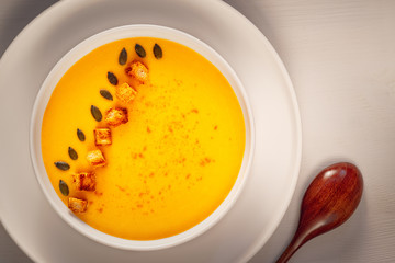  cream pumpkin soup with seeds, pepper and bread on a wooden table
