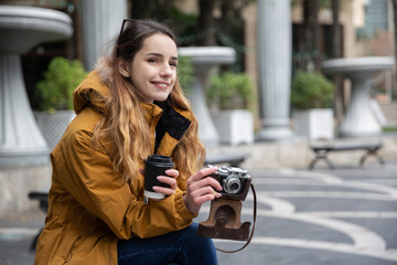 Fototapeta na wymiar Photo of young tourist girl drinking coffee on streets of Baku. Moody photos of teenager girl visiting city