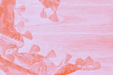 Orange scarf with tassels on a pale pink coral corol shabby background