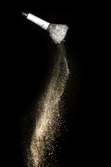 golden powder splash and brush for makeup artist or graphic design in black background