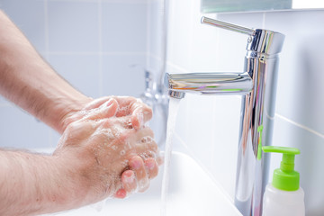 Washing hands with soap in the bathroom