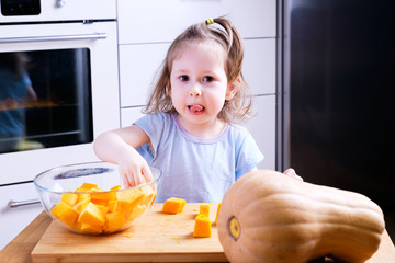 little girl helps her mother prepare a pumpkin