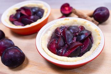Traditional German glazed plum tartelettes in miniature pie dishes with cinnamon sticks