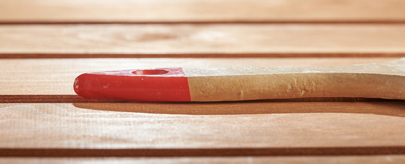 The wooden handle of the brush on the floor. Freshly painted wood surface background.