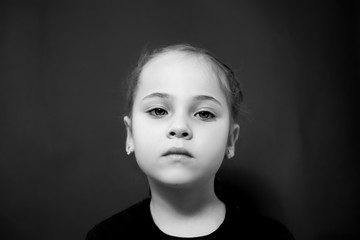 Black and white photo portrait of a girl who looks at the camera with sadness.