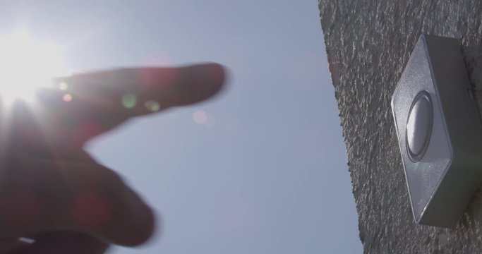 Ringing Doorbell with Protective Gloves and without Male and Female Fingers with Sun Flares and Blue Sky a Concept of Covid-19 Coronavirus Protection
