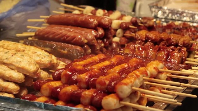 Korean street food, spicy sausage, fish cake, grilled chicken stacked on a food stall.
