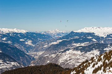 Panoramic view down a mountain valley with paragliders