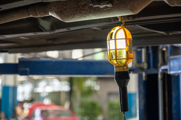 Inspection lamp hanging under car suspension for maintenance.