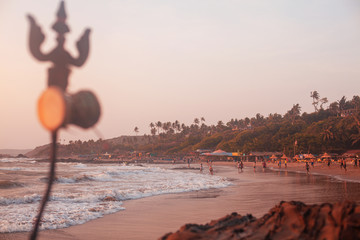 Trident totem near Shiva Face Rock Carving on Vagator Beach, Goa, India. Beautiful sunset and shore...