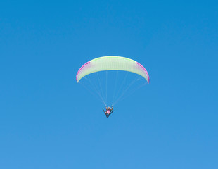 Paraglider flying against blue sky background