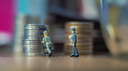 Miniature people standing on coins.and work on coins
