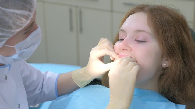 Orthodontist doctor putting silicone invisible transparent braces in girl's teeth in stomatology clinic. Portrait of girl, side view. Correcting teeth. Oral hygiene and treatment, cure in dentistry.