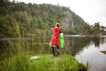 Fototapeta na wymiar Full length behind of mother and daughter by lake pointing