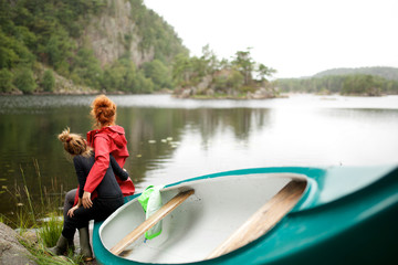 Fototapeta na wymiar mother and daughter sitting on kayak by lake