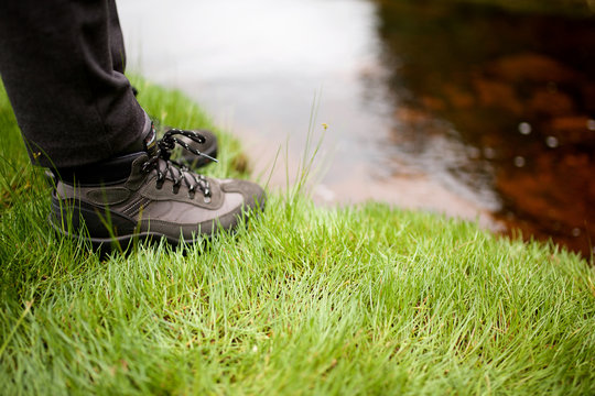 hiker boots standing on grass by water