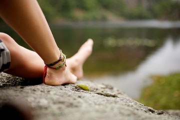 girl sitting barefoot by lake