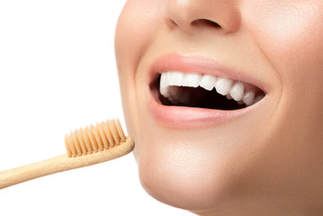 Female mouth with white teeth and bamboo toothbrush