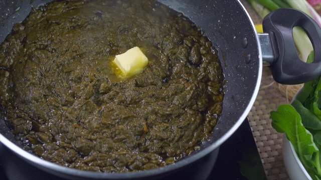 Closeup shot of Sarson ka saag being cooked in a pan - Traditional Punjabi food. High angle shot of delicious Saag with butter  a Punjabi cuisine eaten during the winter season in north India