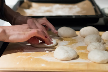 mani di donna che preparano pasta per il pane fatto in casa su tagliere cosparso di farina