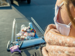 Woman bying food in supermarket, Panic shopping during pandemic, food supplies in trolley, wearing medical mask and rubber gloves,  coronavirus times