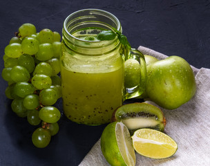 two green healthy smoothies made from apples, spinach, avocado, salad, kiwi on a wood background