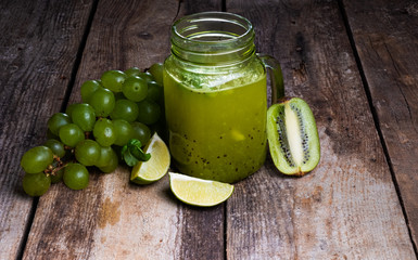 two green healthy smoothies made from apples, spinach, avocado, salad, kiwi on a wood background