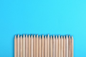 Lot of wooden pencils on blue paper background