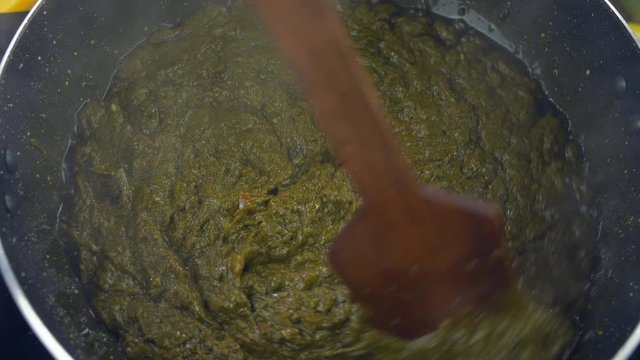 Closeup shot of Sarson ka saag being cooked in a pan - Traditional Punjabi food. Top view shot of hands cooking delicious Saag  a Punjabi cuisine eaten during the winter season in north India 