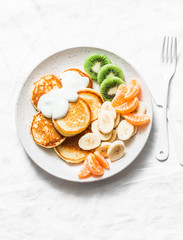 Delicious breakfast or snack - pancakes with fruit and cream fresh on a light background, top view