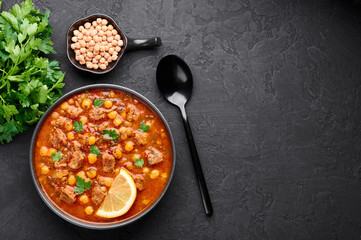 Moroccan Harira Soup in black bowl at dark slate bakcground. Harira is Moroccan Cuisine dish with...