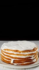 biscuits cake with white cream. 
a lot of cream on the cake. white plate black background. closeup