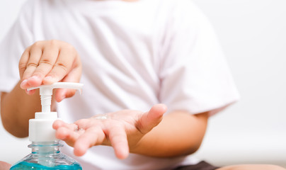 Closeup Asian little child boy sitting applying bottle pump dispenser sanitizer alcohol gel cleaning washing hands yourself, COVID-19 or coronavirus protection concept, isolated on white background