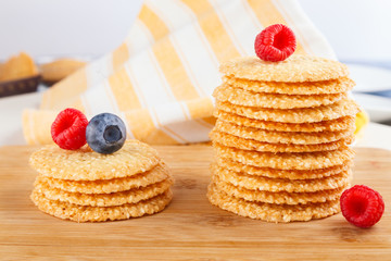 Stack of cookies with sesame seeds and fresh raspberry and blueberries on wooden board. healthy food. Close up view