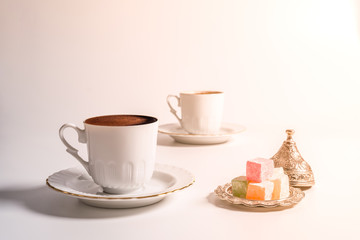 A cup of Turkish coffee with Turkish delight in traditional white porcelain Turkish coffee cup