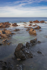 Fototapeta na wymiar Volcanic rocks in Atlantic ocean, long exposure photography, horizon with sunset light, Puerto de la Cruz coastline, Tenerife, Canary islands, Spain